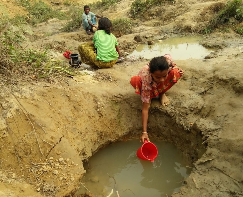 A Rohingya girl getting water out of a whole